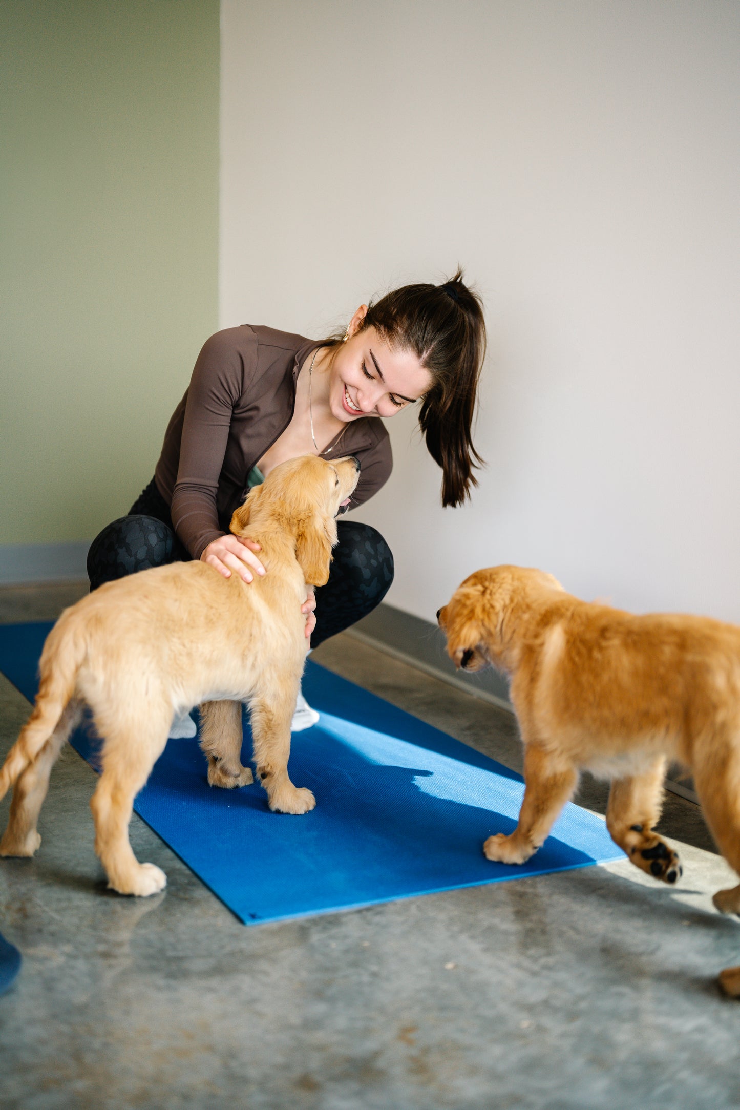 Jeune femme interagissant avec deux chiots Golden Retriever pendant une séance de Puppy Yoga à Euphorie Chiot, Rive-Nord de Montréal. Activité relaxante et immersive avec des chiots.